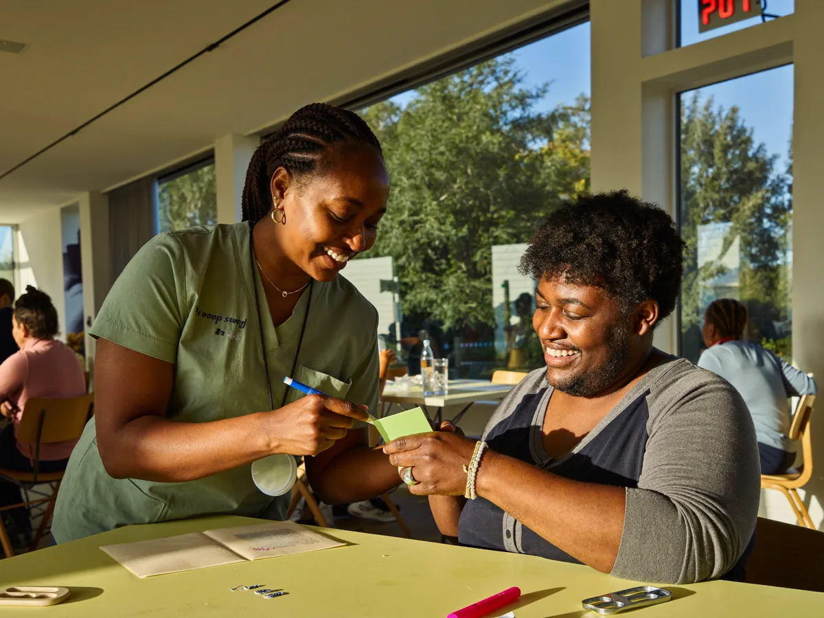 A direct support professional at My Choice smiling with a guest during an activity